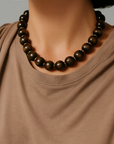 Person wearing a brown beaded necklace against a neutral background