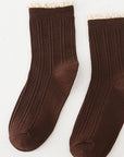 Pair of brown socks with white trim on a light gray background