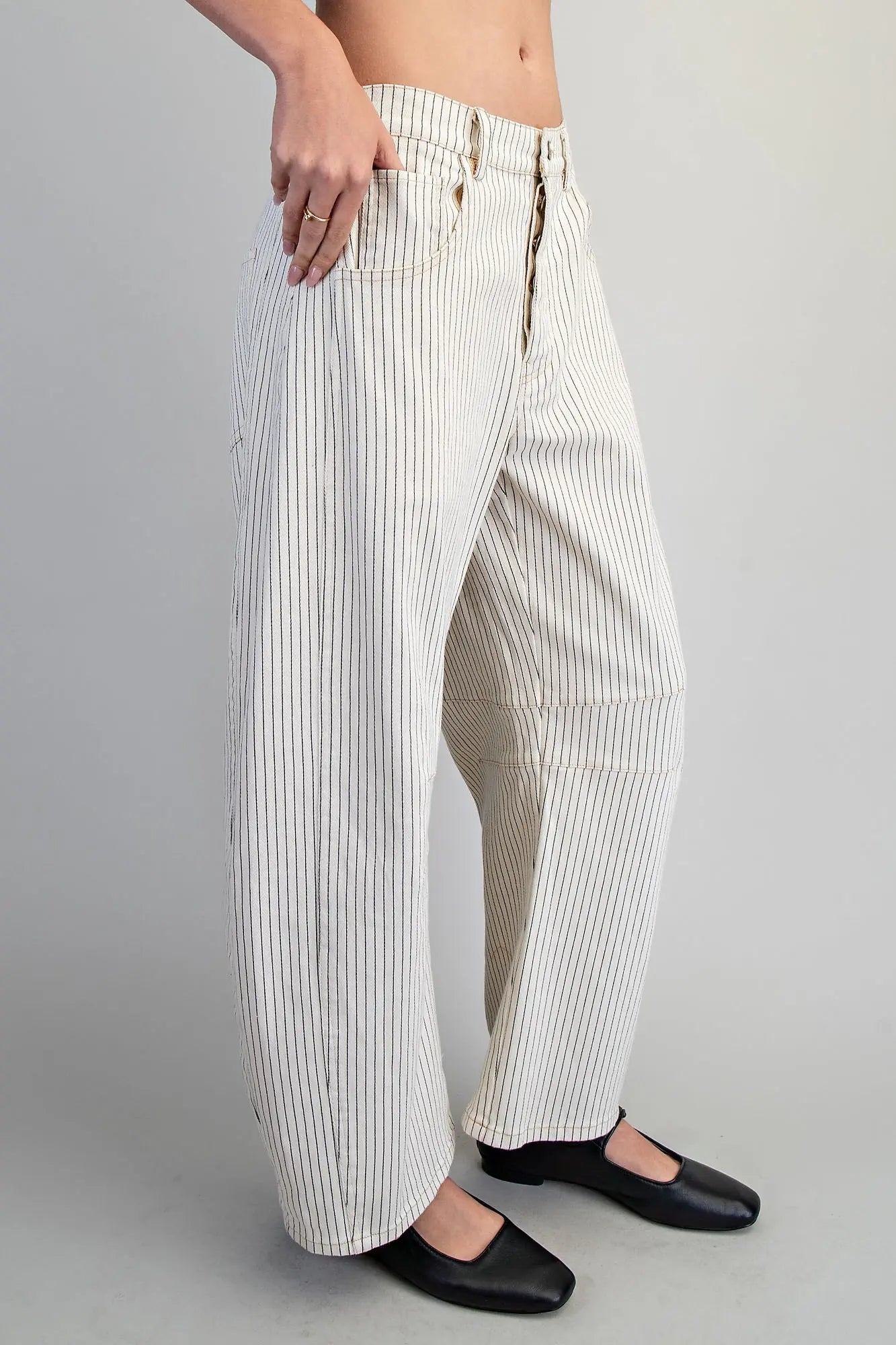 Person wearing white and gray striped pants on a plain background