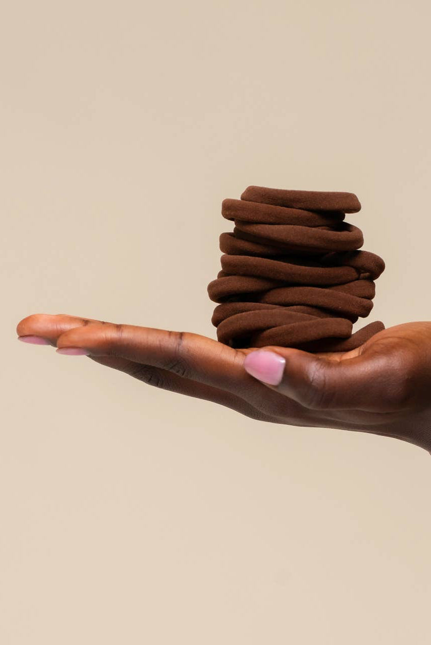 Hand holding a stack of brown cookies against a beige background