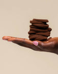 Hand holding a stack of brown cookies against a beige background