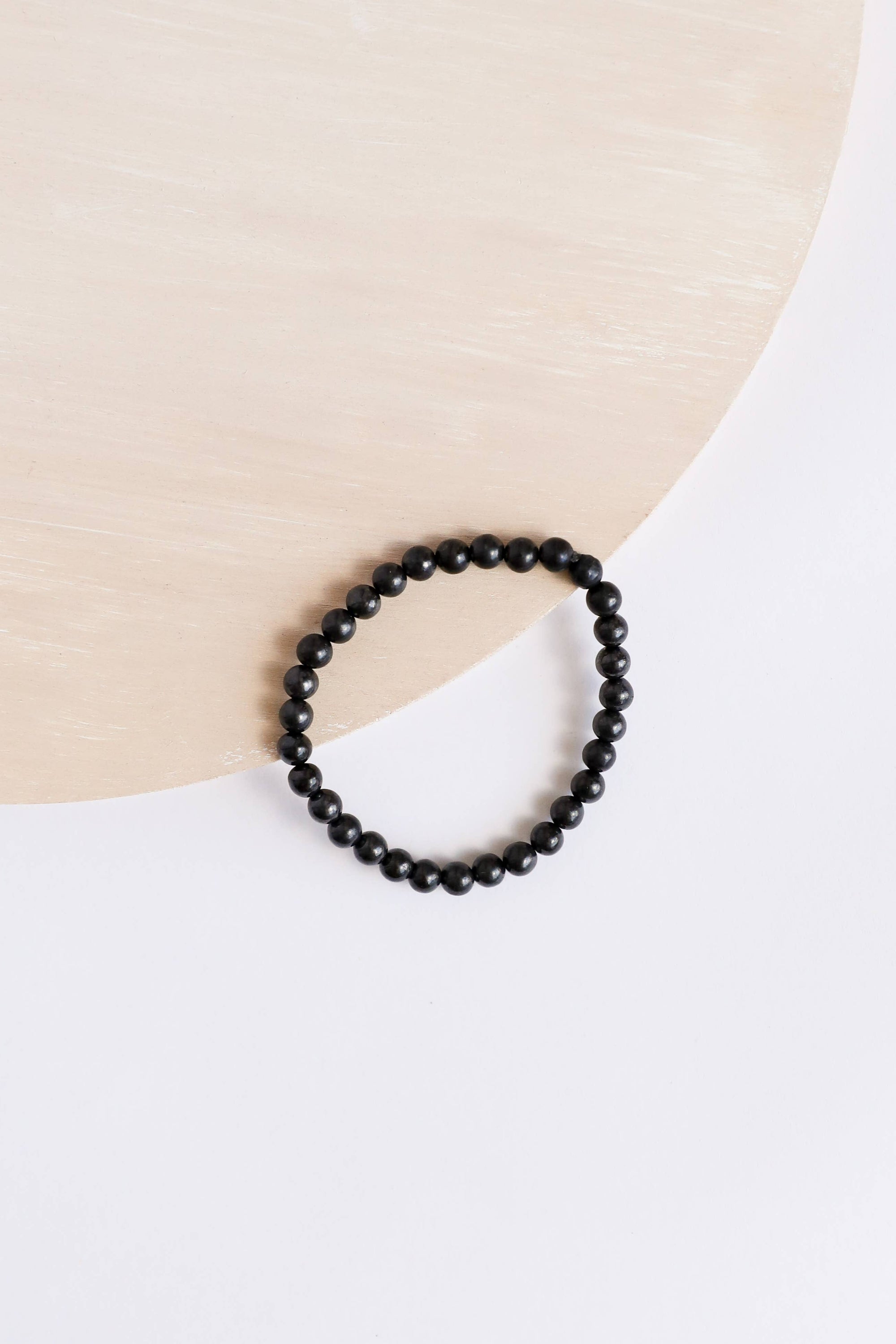 Black beaded bracelet on a white shirt with a beige background