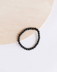 Black beaded bracelet on a white shirt with a beige background