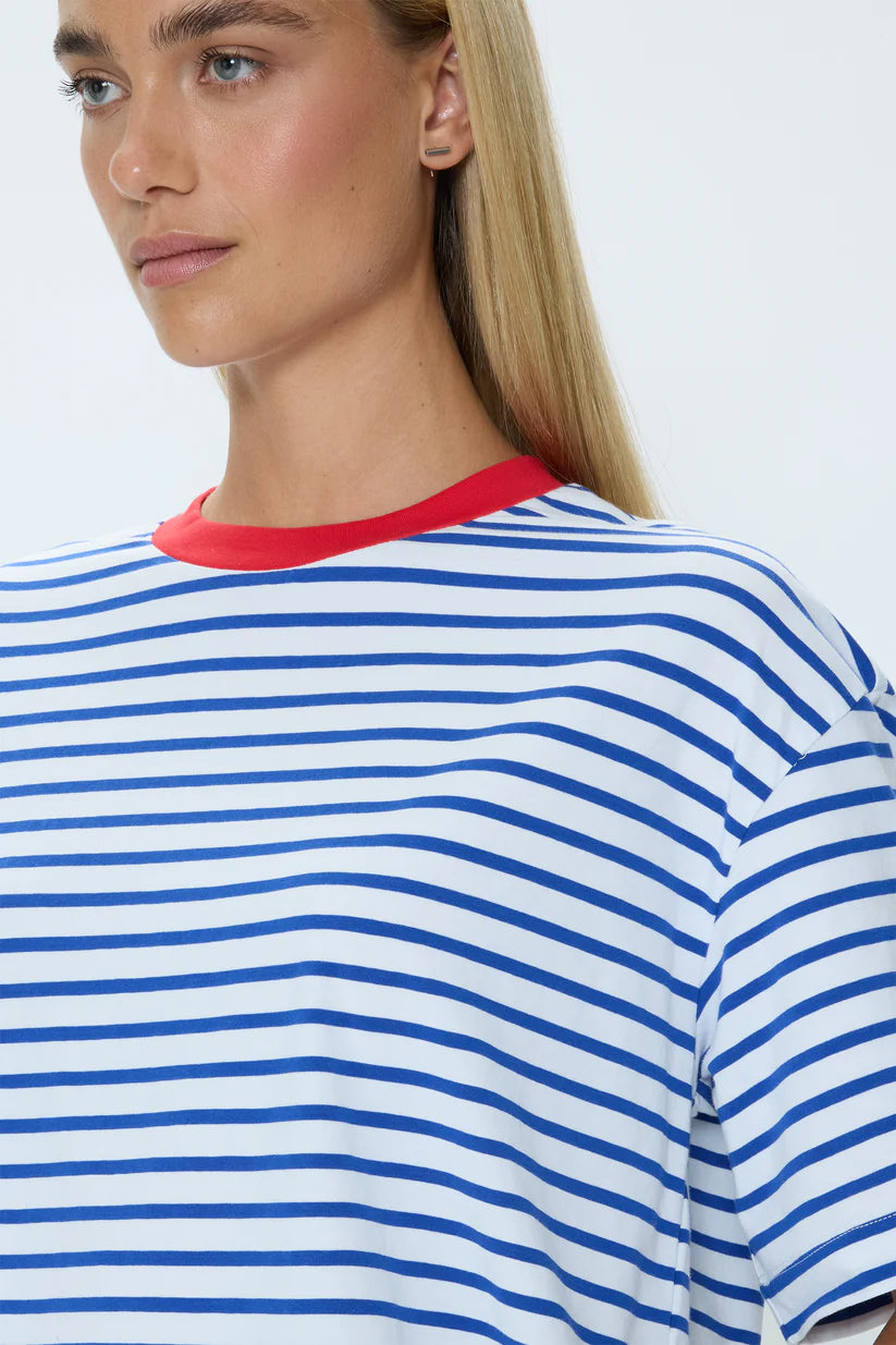 Person wearing a blue and white striped shirt with a red collar on a plain background