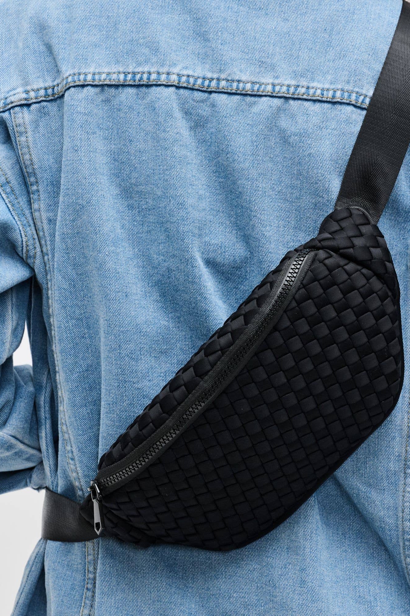 A woman wearing a beige woven neoprene belt bag with an adjustable strap, viewed from the back.