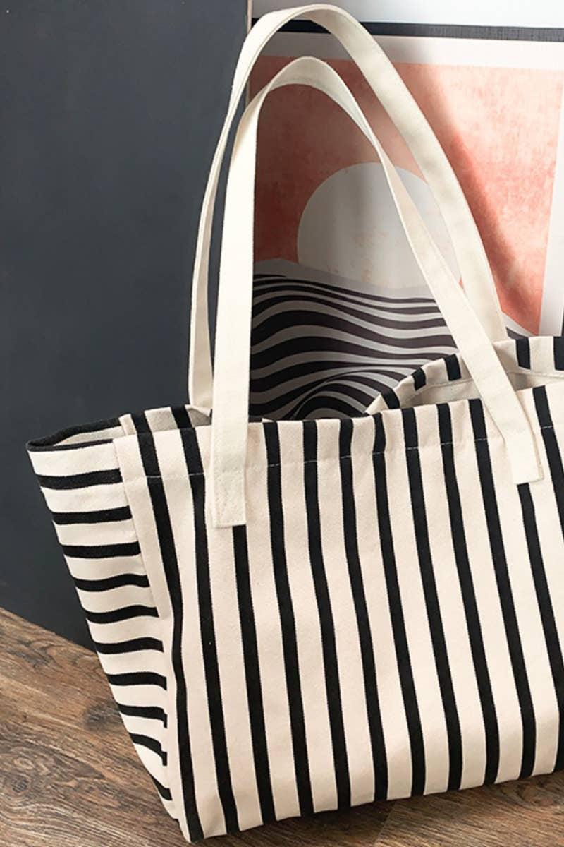Black and white striped tote bag on a wooden surface with a blurred background