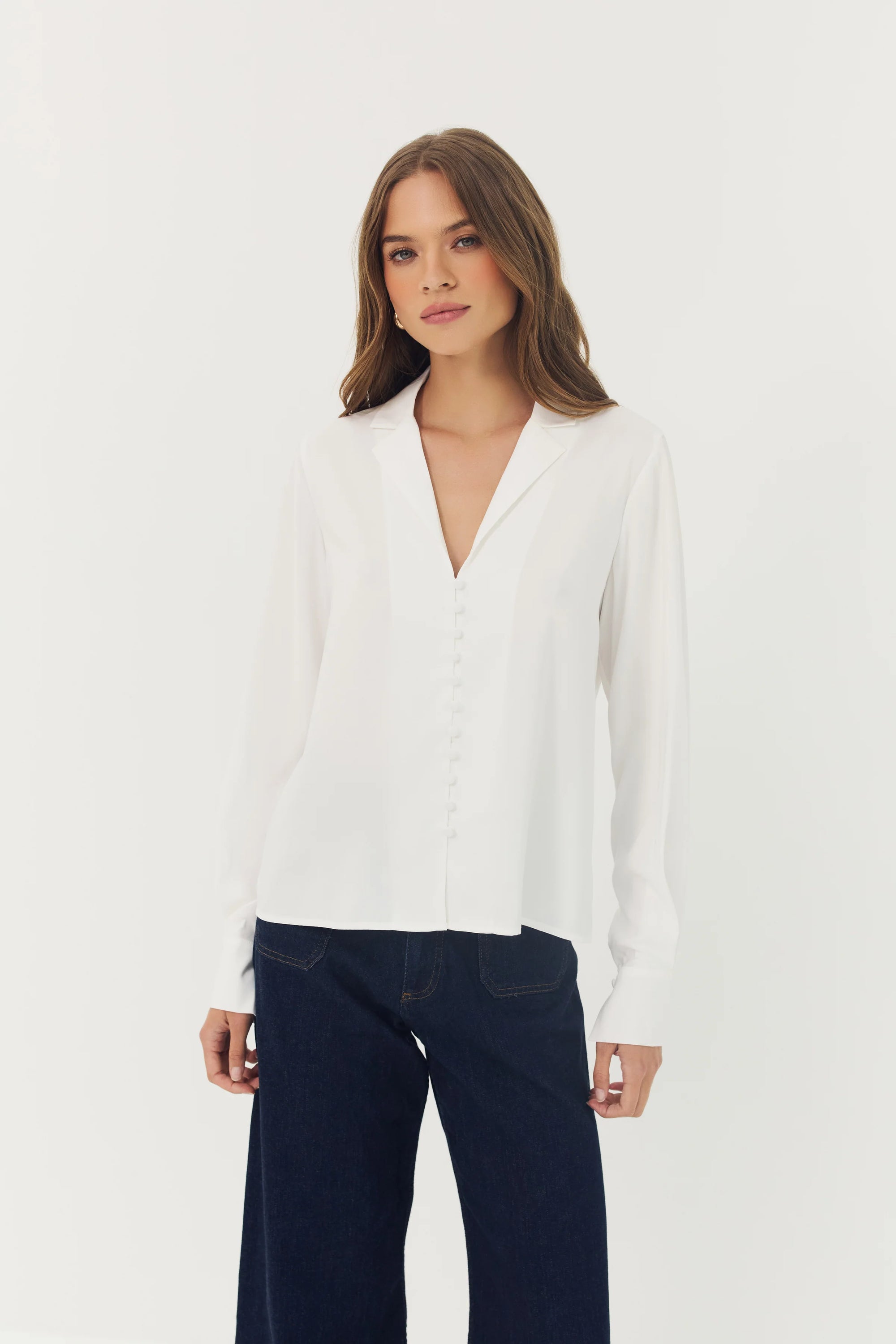 Woman wearing a white blouse and dark pants on a white background
