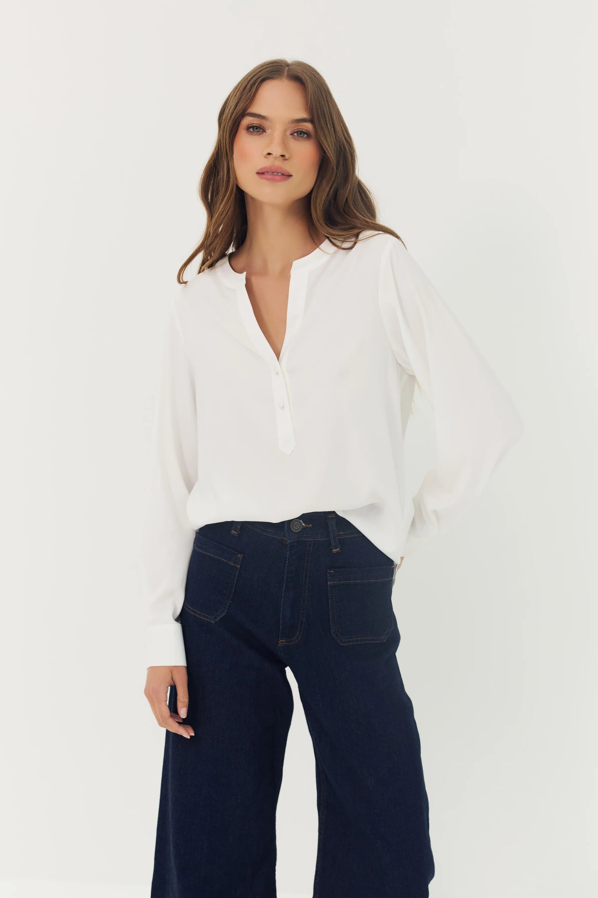 Woman wearing a white blouse and dark blue jeans on a white background