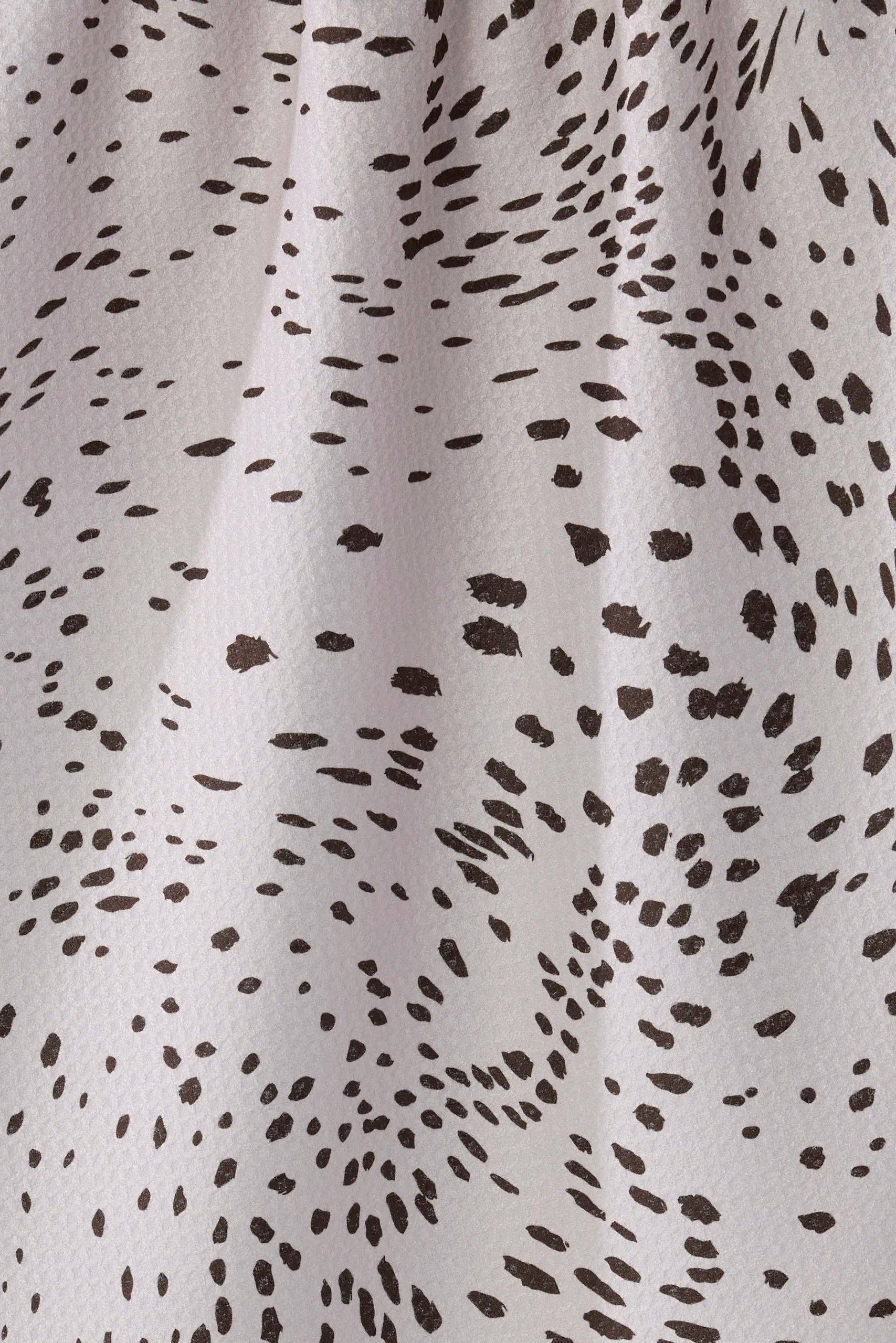 Close-up of a fabric with black spotted pattern on a gray background
