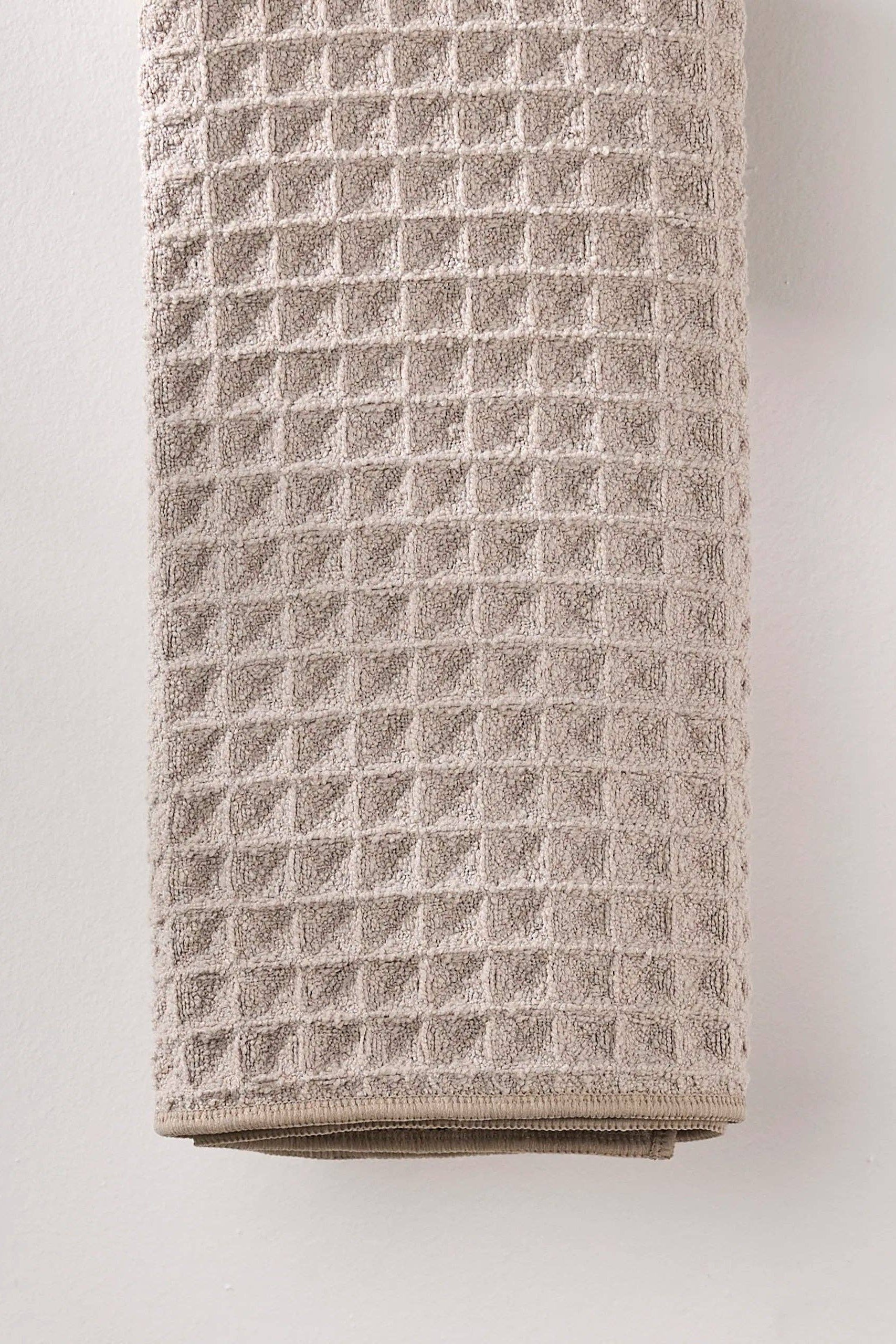 Folded beige towel with a diamond pattern on a light gray background