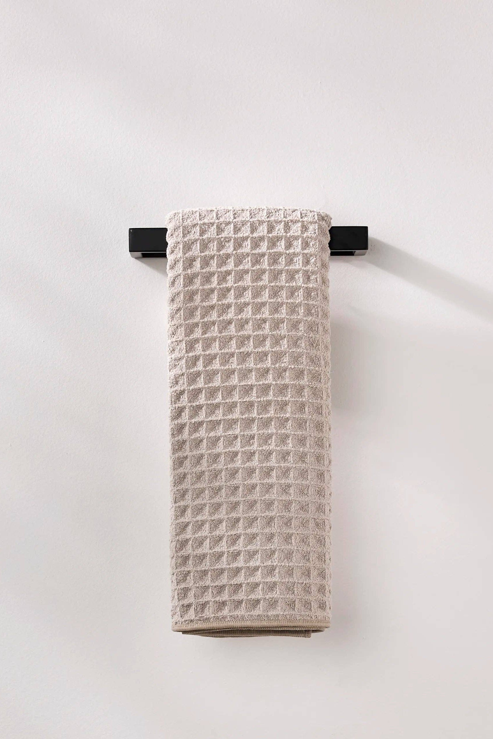 Textured towel hanging on a black rack against a white background