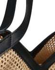 Close-up of a woven handbag with a black handle on a white background
