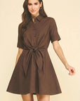 Woman wearing a brown dress with a belt on a beige background