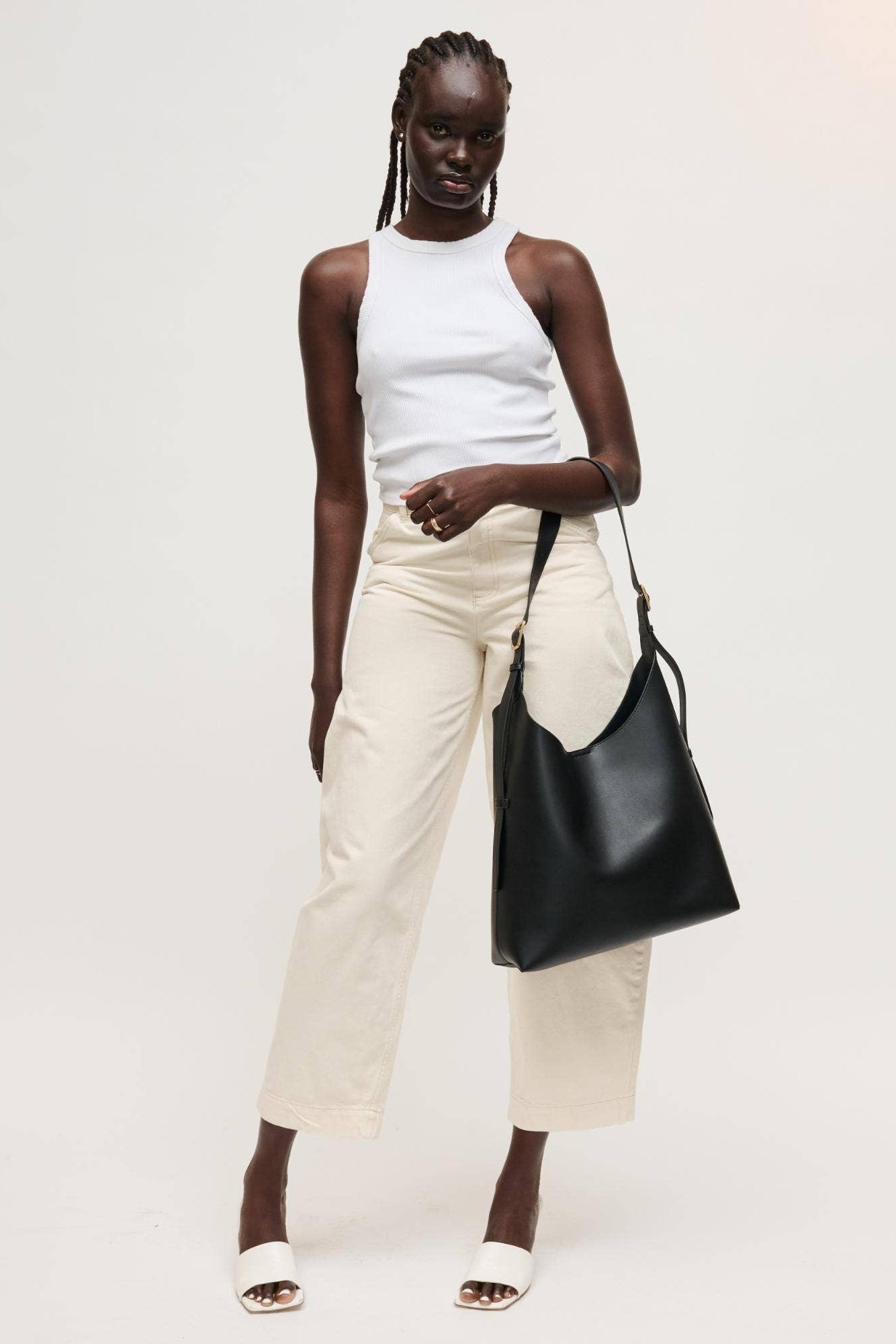 Woman holding a black handbag against a white background