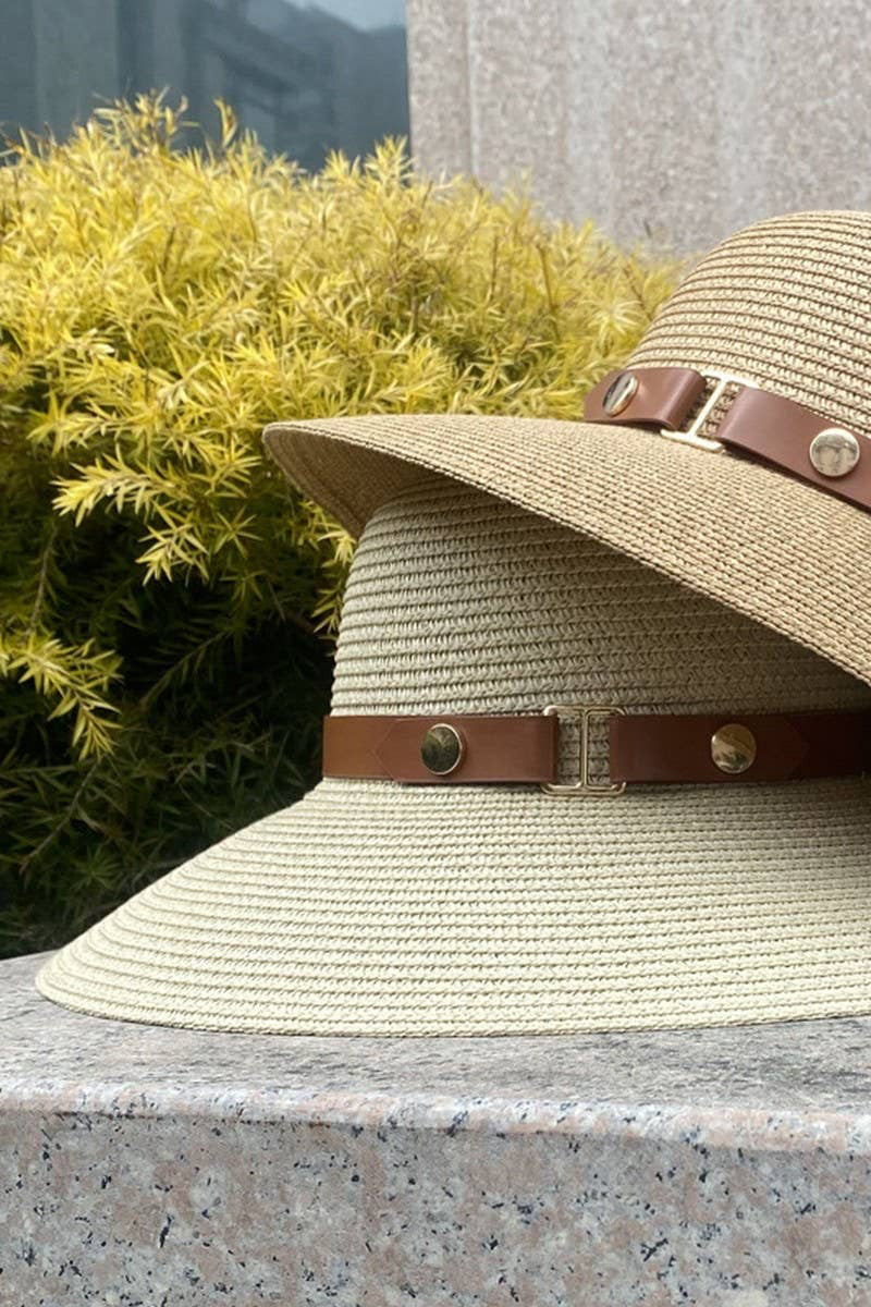 Beige straw hat with brown leather bands on a stone surface