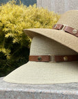 Beige straw hat with brown leather bands on a stone surface