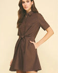Woman wearing a brown dress against a beige background
