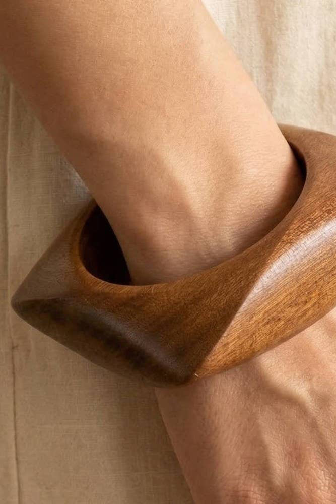 Wooden cuff bracelet on a wrist with a neutral background