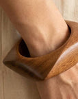 Wooden cuff bracelet on a wrist with a neutral background