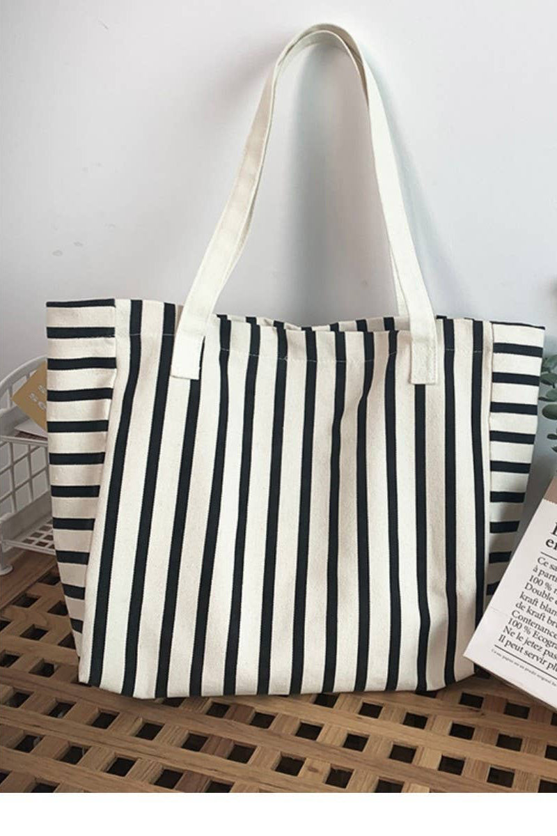 Striped tote bag on a wooden surface with a plant and card in the background