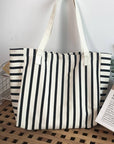 Striped tote bag on a wooden surface with a plant and card in the background