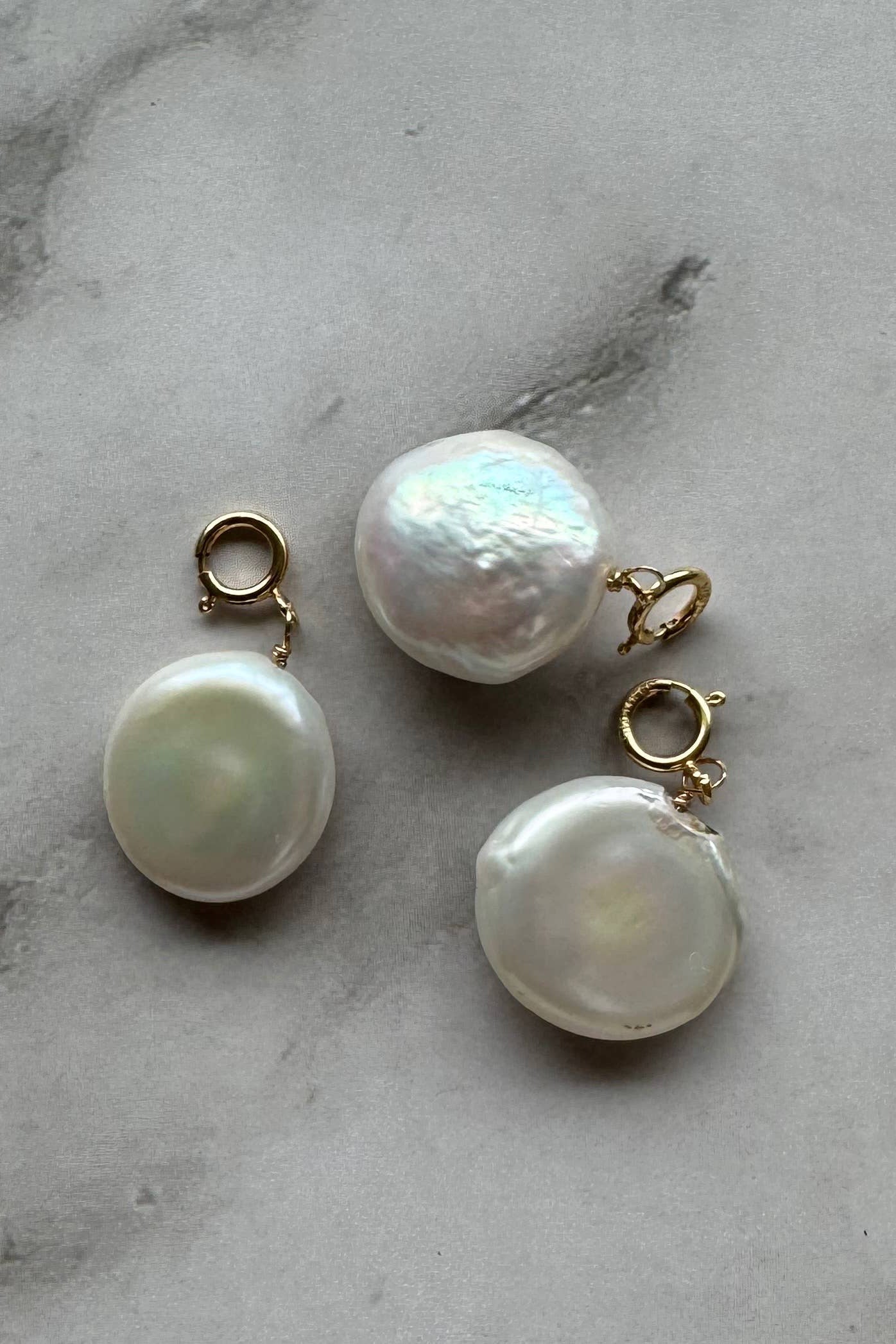 Three pearl earrings on a marble surface