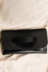 Black clutch bag on a beige fabric background