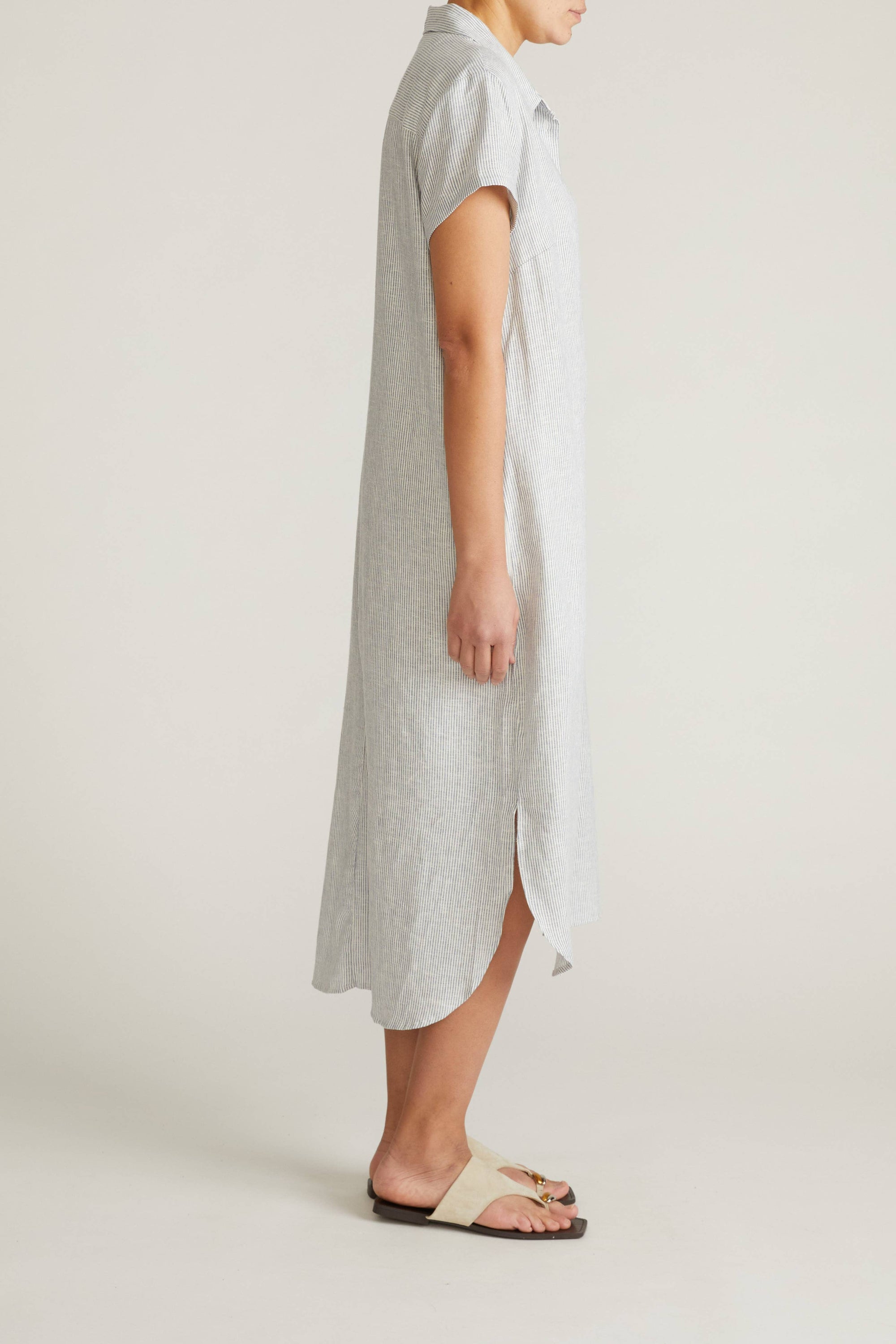 Woman wearing a long, light gray dress against a plain background