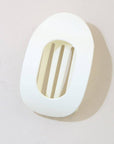 White wall light fixture with a gold grille on a light gray background