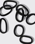 Set of black hair ties on a light gray background