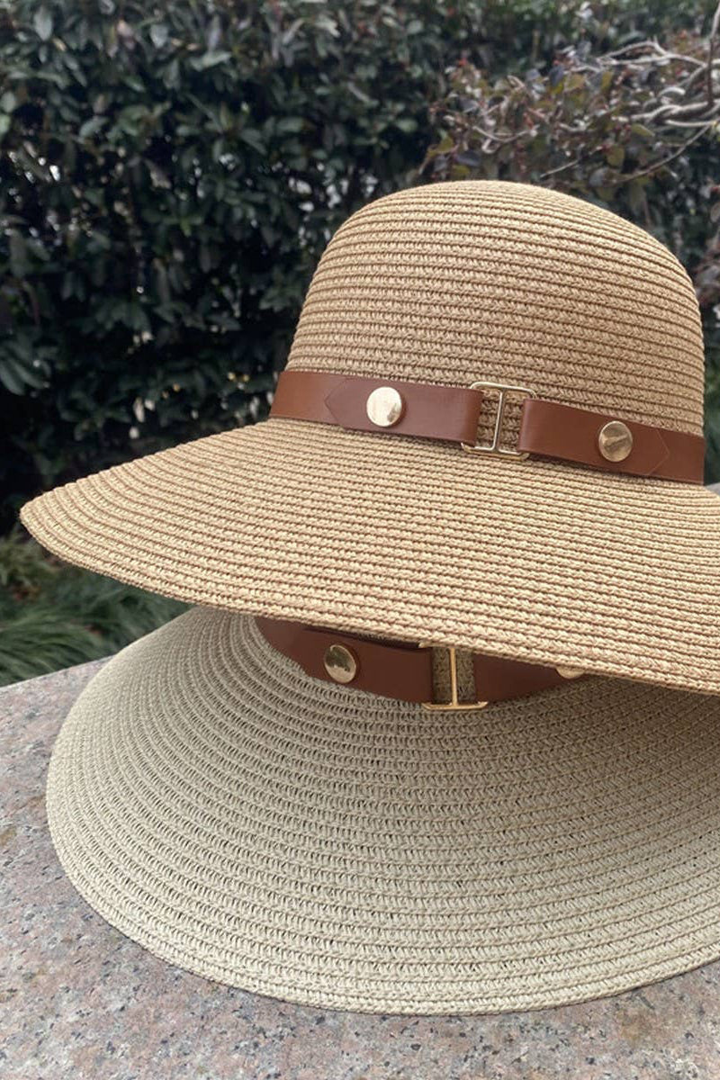 Beige straw hat with a brown leather band on a stone surface with a blurred natural background