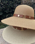 Beige straw hat with a brown leather band on a stone surface with a blurred natural background
