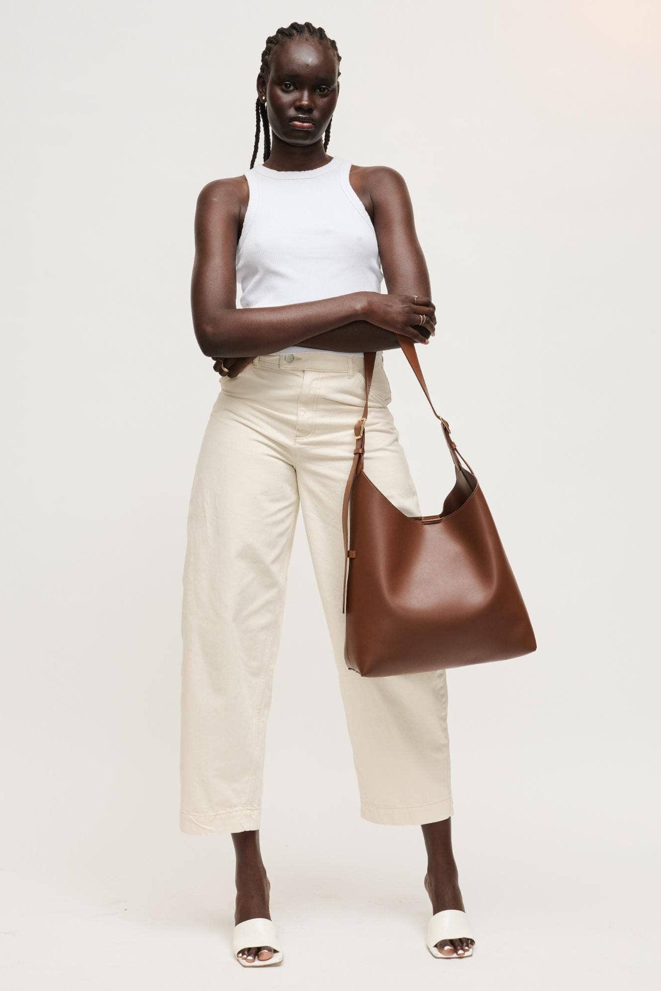Woman holding a brown leather bag against a plain background