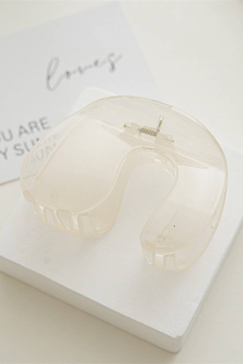 Clear acrylic heart-shaped object on a white surface with a small card in the background.