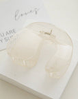 Clear acrylic heart-shaped object on a white surface with a small card in the background.