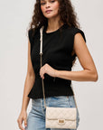 Woman holding a white quilted handbag against a plain background