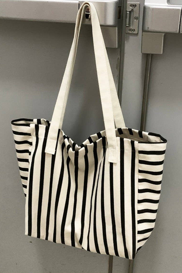 Black and white striped tote bag hanging on a metallic surface