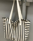 Black and white striped tote bag hanging on a metallic surface