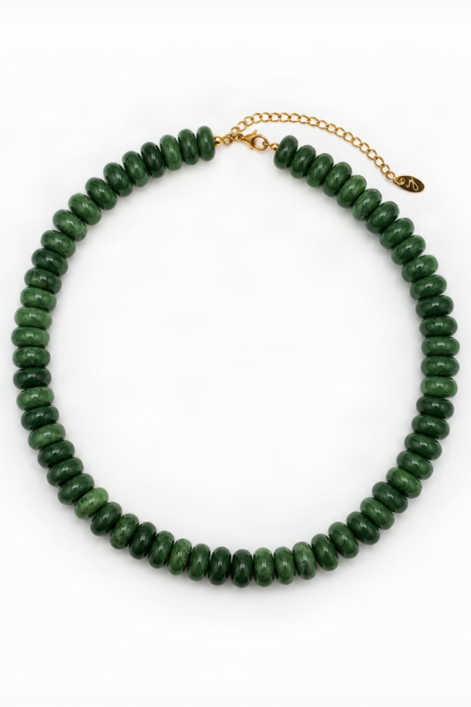 A green beaded necklace made of faceted round beads, arranged in a circle on a white background, with a gold-tone chain extender and clasp.