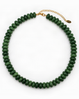 A green beaded necklace made of faceted round beads, arranged in a circle on a white background, with a gold-tone chain extender and clasp.