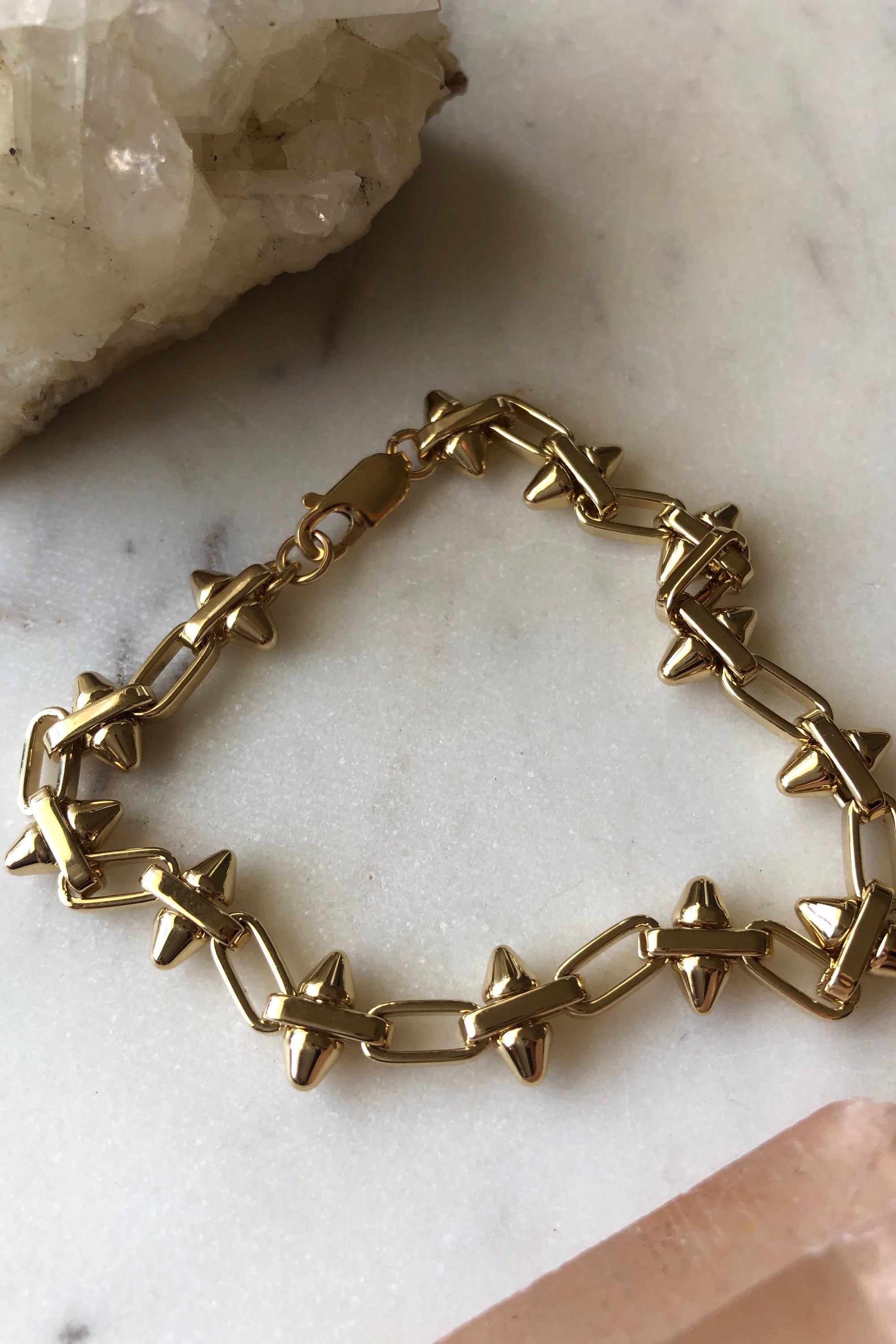 Gold chain bracelet on a marble surface with crystals