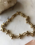Gold chain bracelet on a marble surface with crystals