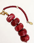 Red beaded bracelet with gold accents on a white background