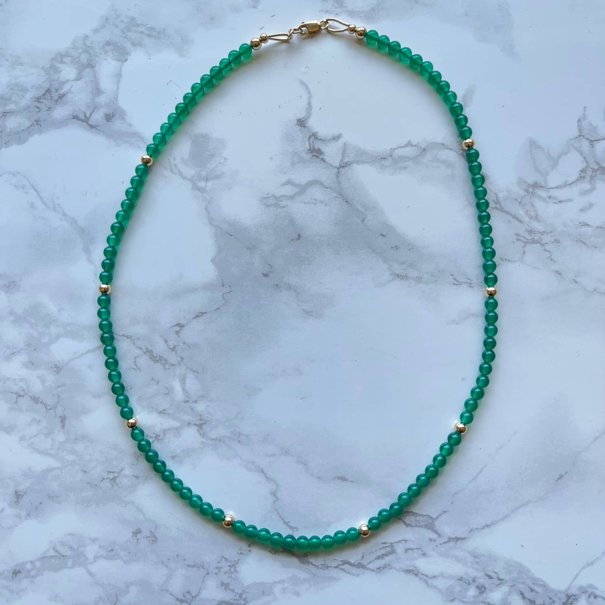 Green beaded necklace on a marble surface