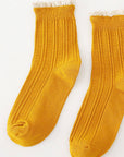 Pair of mustard yellow socks with lace trim on a white background