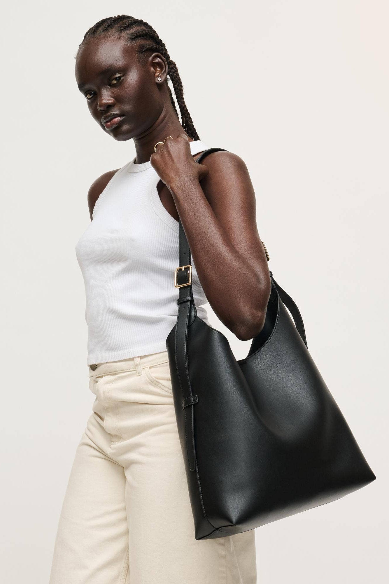 Woman holding a black leather handbag against a plain background