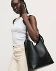 Woman holding a black leather handbag against a plain background