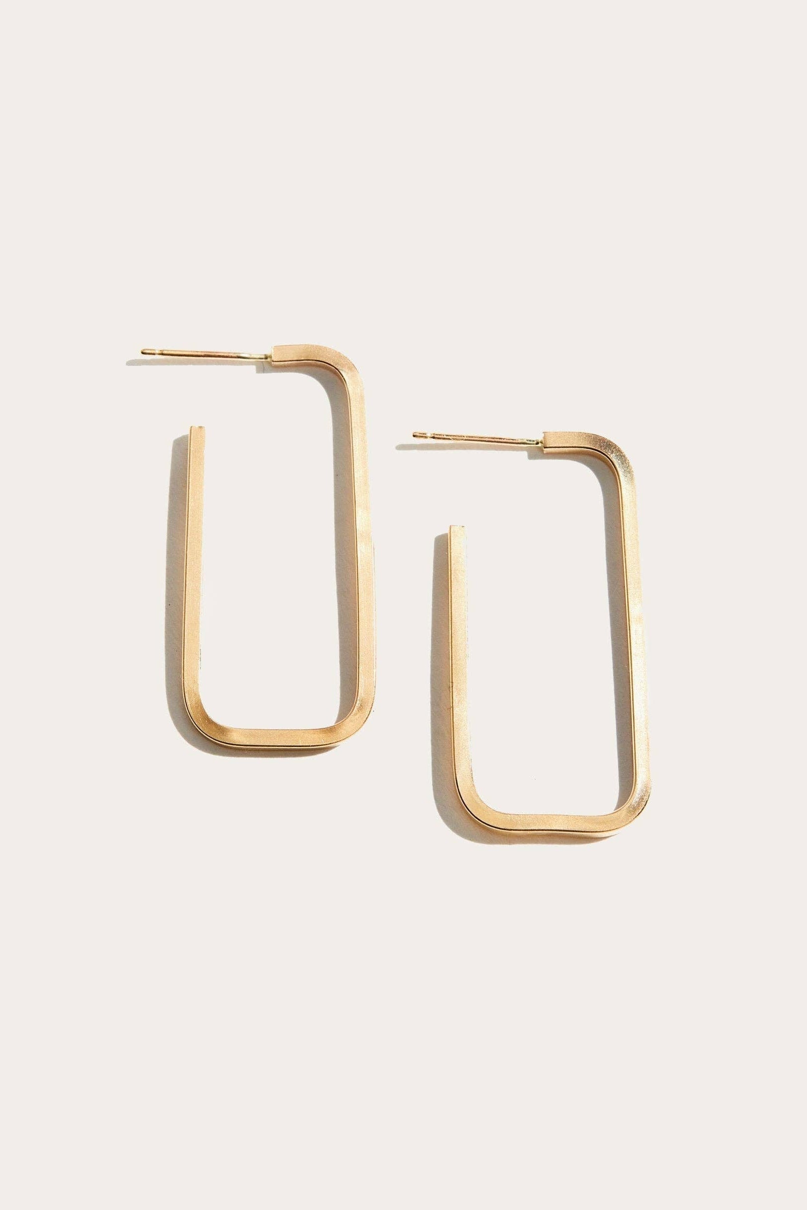 Gold hoop earrings on a light beige background