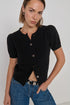 Woman wearing a black short-sleeve button-up shirt and blue jeans against a plain background