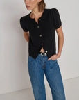 Woman wearing a black top and blue jeans against a white background